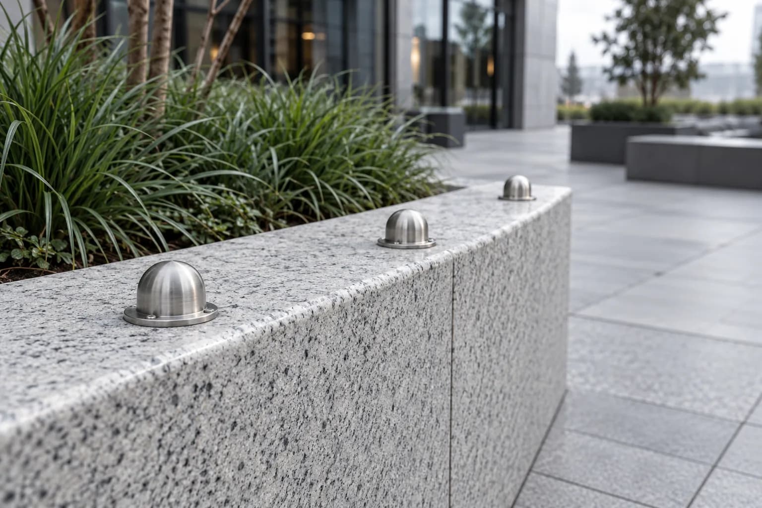 Rounded stainless steel skate deterrents mounted along a granite planter ledge