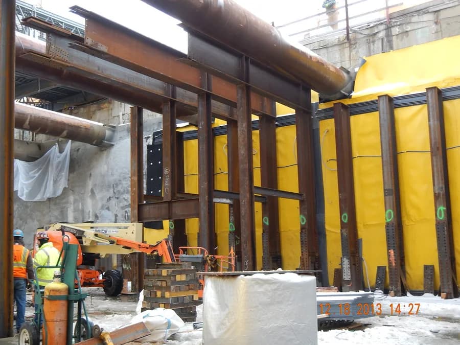 Workers coordinating installation beneath structural beams